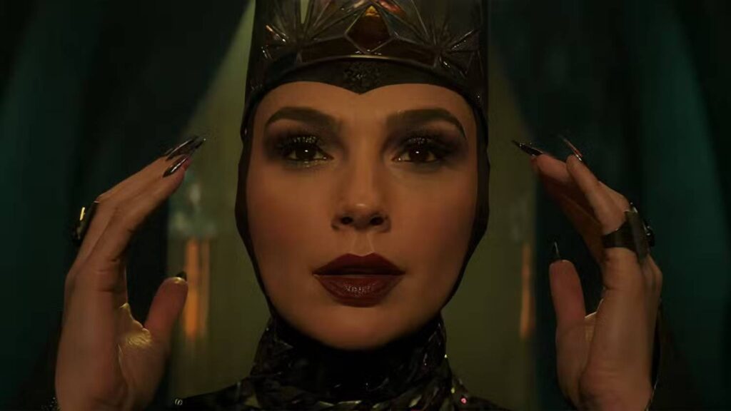 gal gadot as the evil queen putting on her crown in snow white